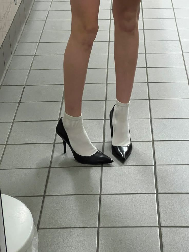 Person wearing black heels and white socks on a tiled floor