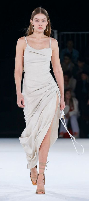 Woman in a light-colored strappy dress with a high slit on a runway