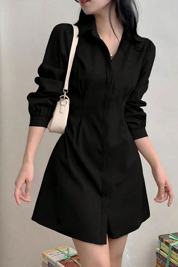 Woman in a black long-sleeve dress with a white shoulder bag