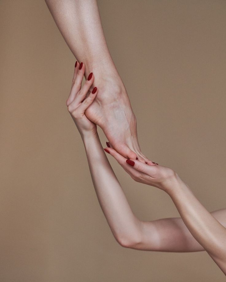 Hands with red nails holding a foot against a warm background