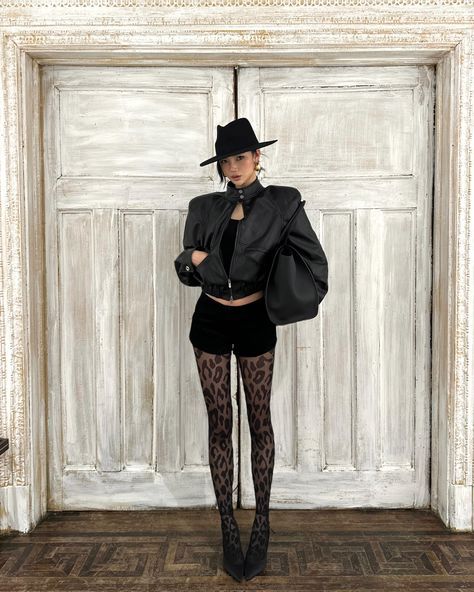 Woman in a black hat and leather jacket with leopard print tights
