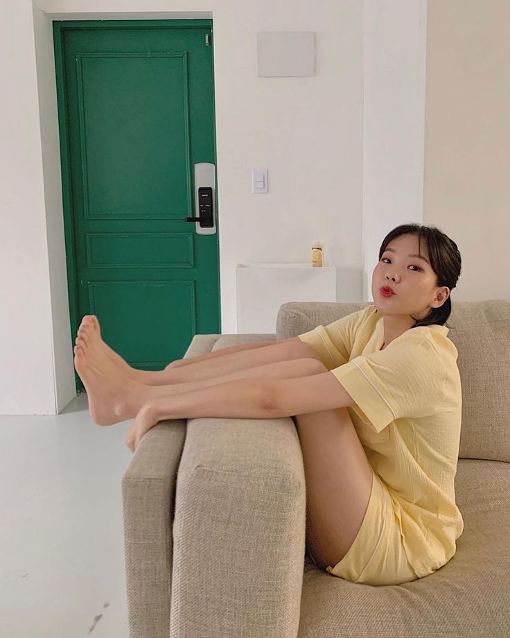 Woman in yellow pajamas sitting on a couch with her feet up