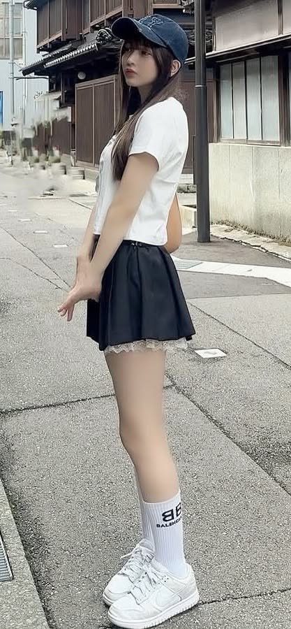Woman in a baseball cap and mini skirt standing on a street