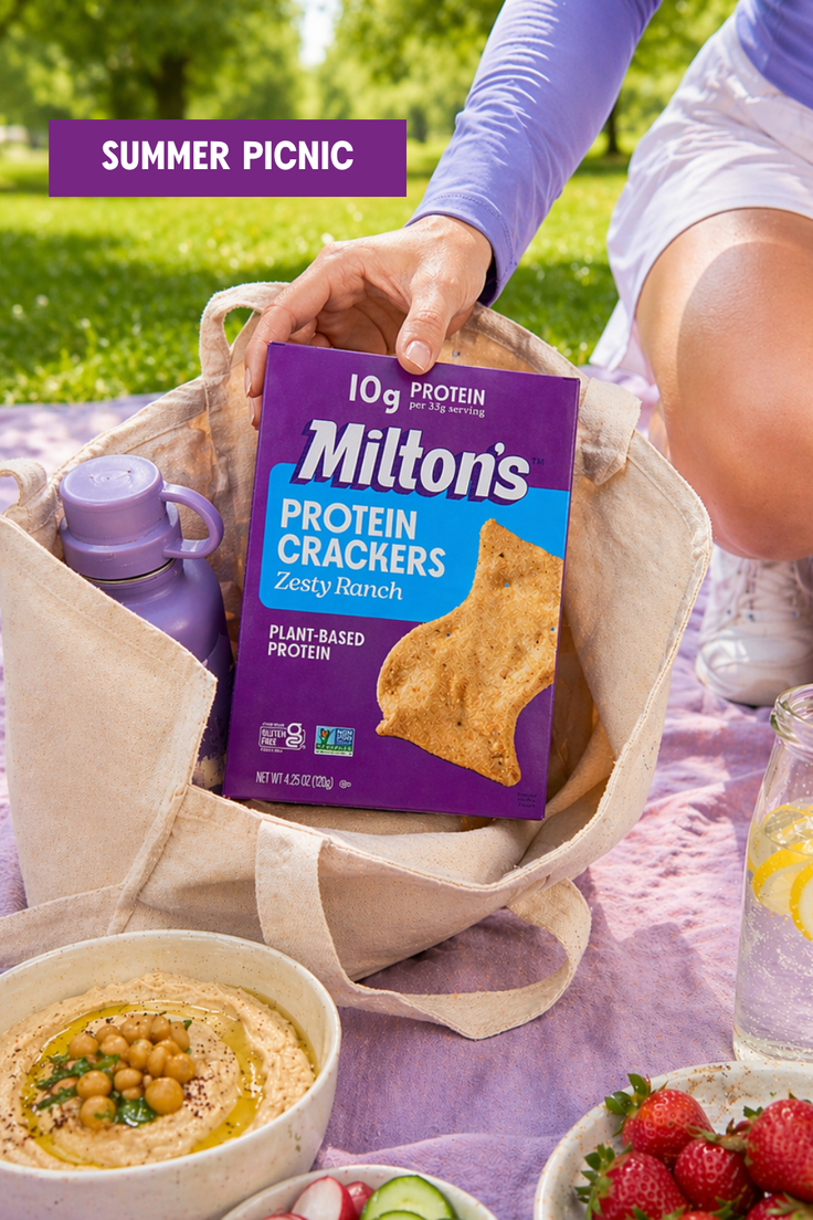 Hand placing a box of protein crackers into a bag during a summer picnic