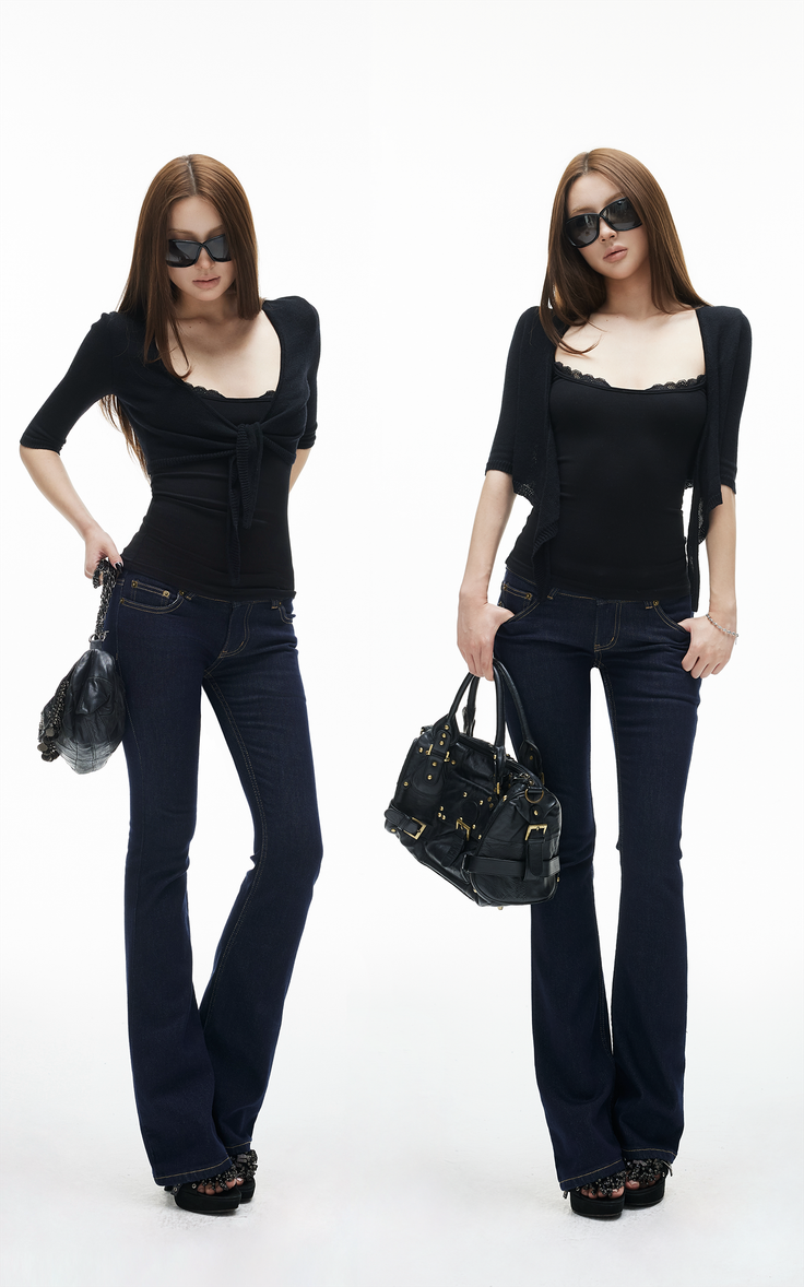 Two women in black tops, dark wash jeans, and sunglasses posing with handbags