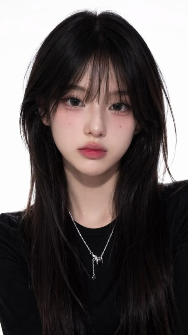 Woman with long black hair and a silver necklace against a white background
