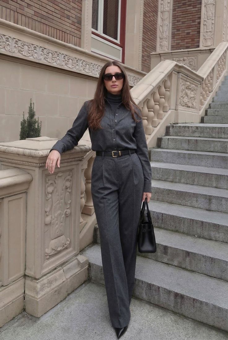 Woman in a gray suit and sunglasses standing on a stone staircase