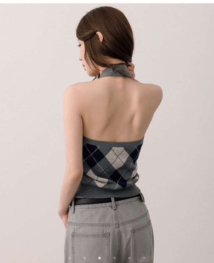 Woman in a gray argyle halter top and jeans, seen from behind
