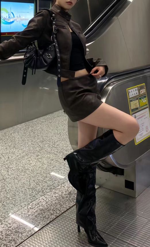 Woman in a leather jacket and mini skirt posing on an escalator