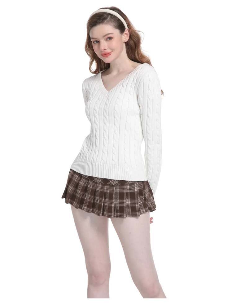 Woman in a white cable knit sweater and brown plaid skirt with a headband