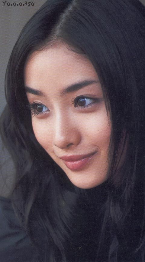 Woman with long black hair looking to the side with a soft smile