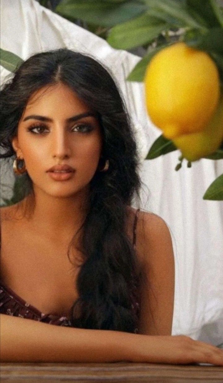 Woman with long dark hair and hoop earrings, with lemons in the foreground