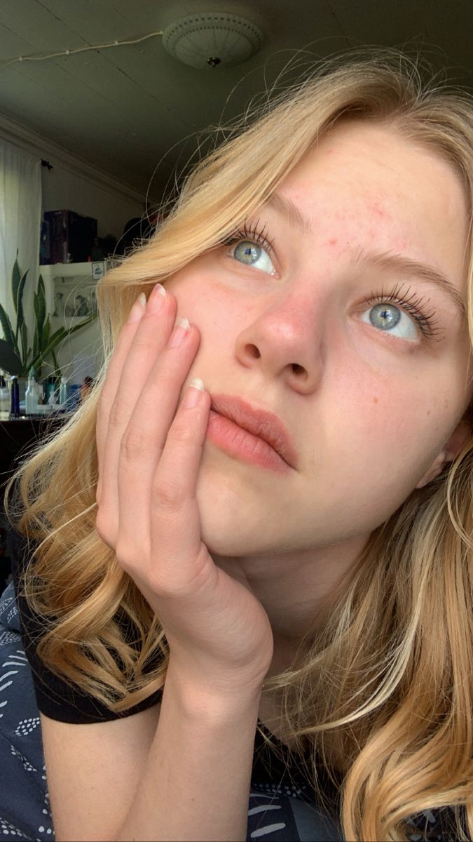 Close up portrait of a blonde woman looking up with her hand on her cheek
