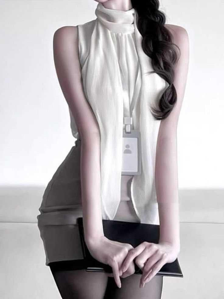 Woman in a sleeveless high-neck top with an ID badge and long dark hair