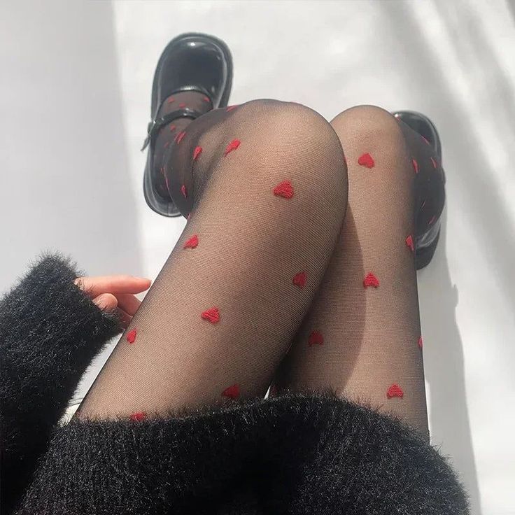 Person wearing black tights with red hearts and mary jane shoes