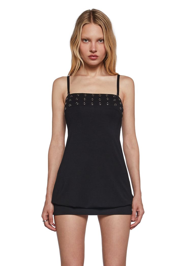 Woman with blonde hair wearing a black dress with metal eyelets