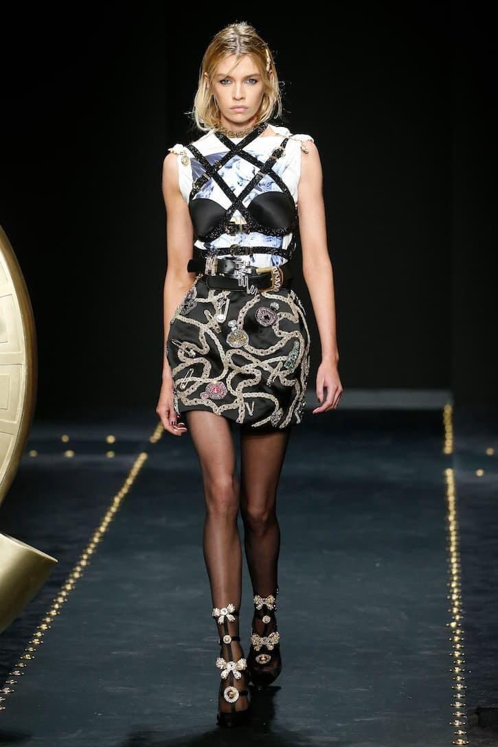 Model in a black and white outfit with a harness top and embellished mini skirt