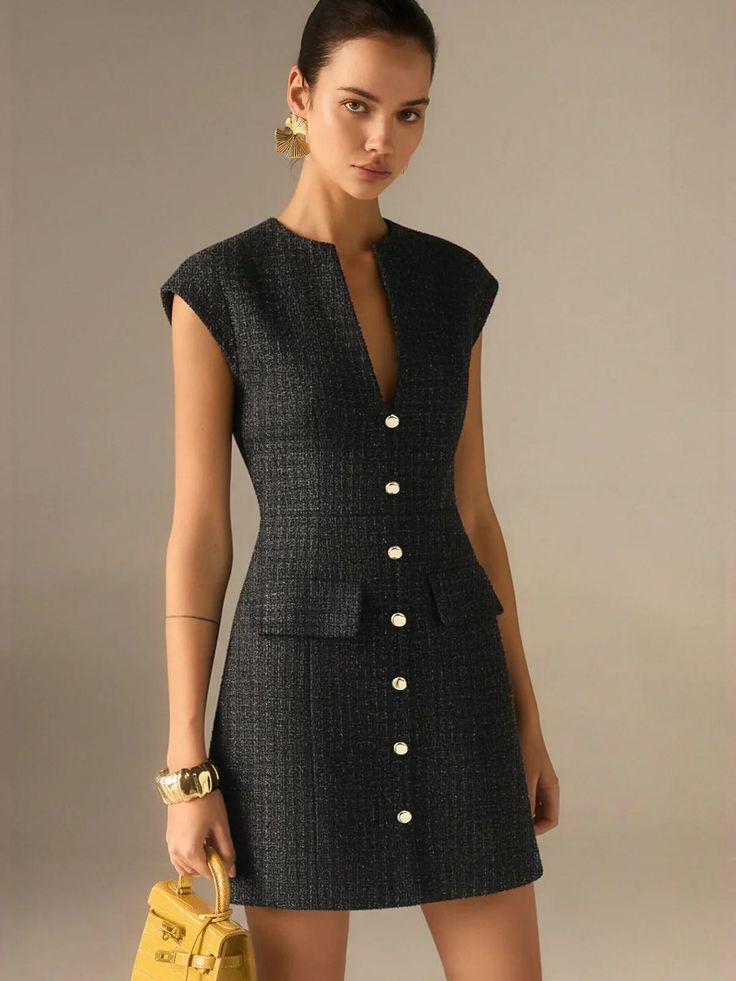 Woman in a dark tweed dress with gold accessories holding a yellow handbag