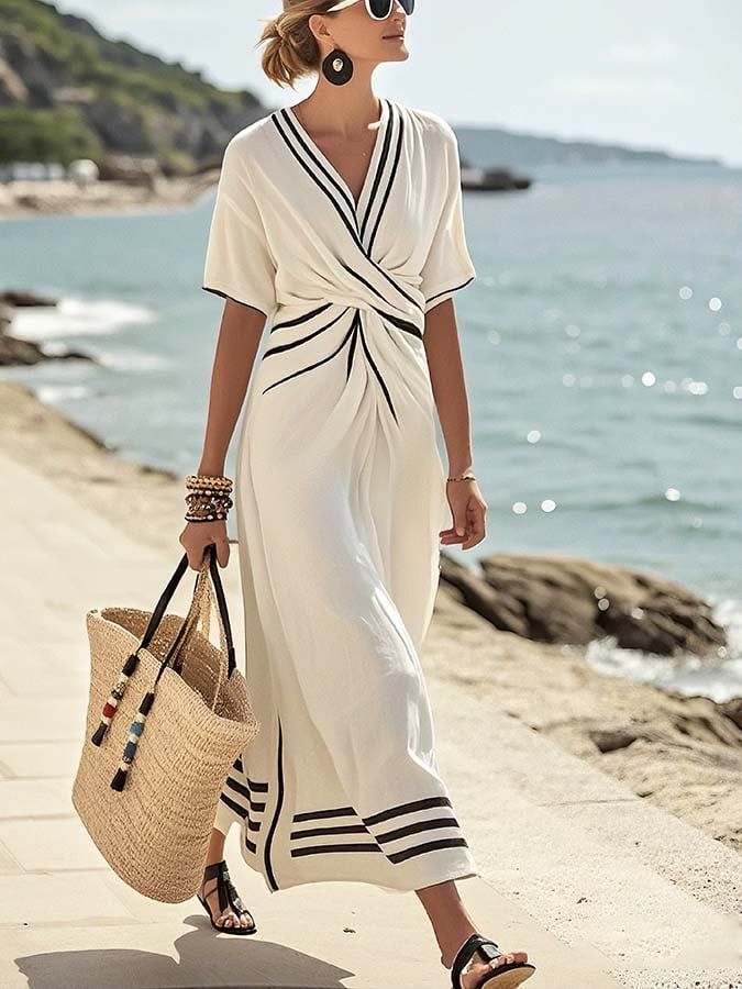 Woman in a white dress with black stripes walking along a beach path