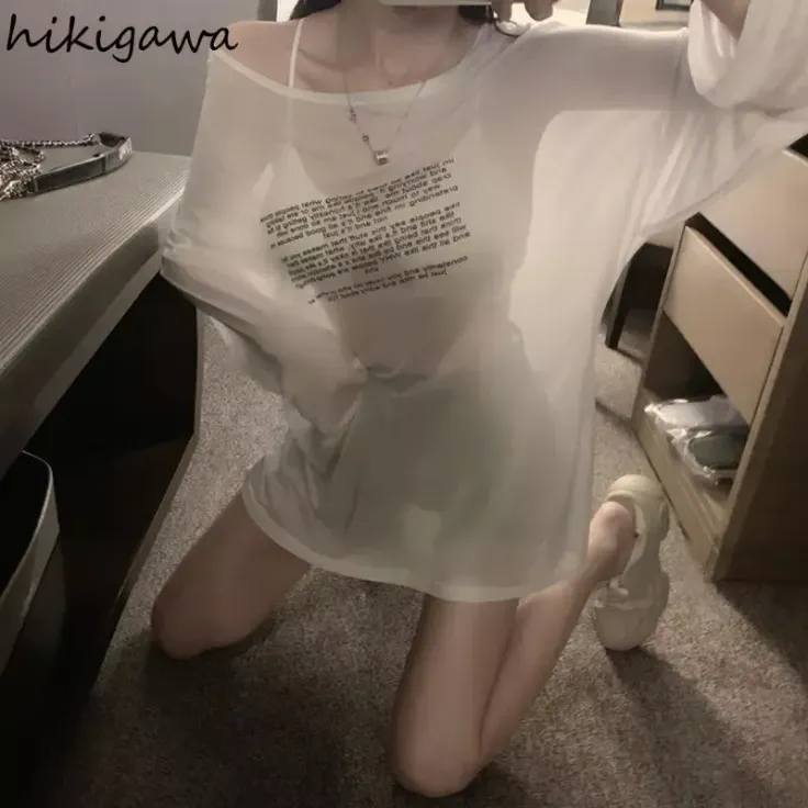 Person in an oversized sheer white shirt kneeling on a carpeted floor