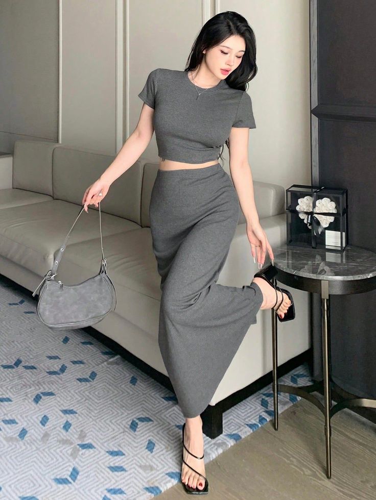 Woman in a gray crop top and maxi skirt posing indoors