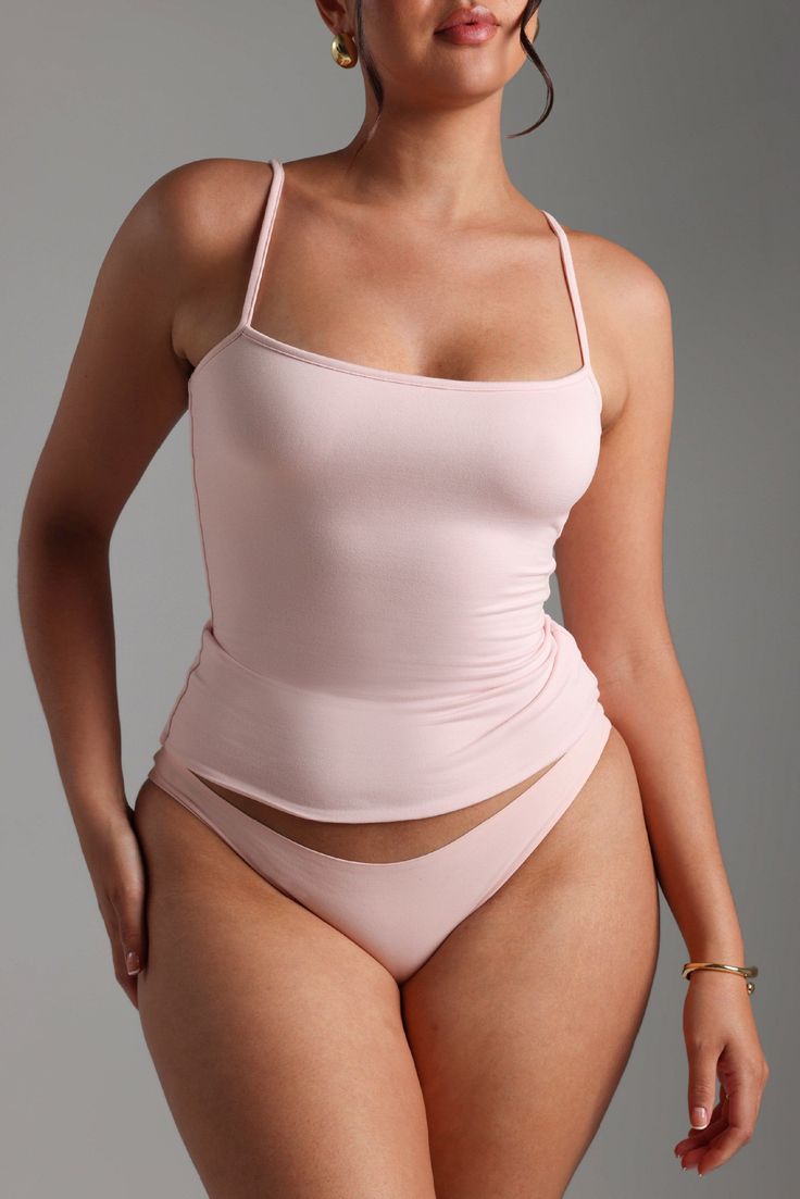 Woman in pink top and underwear with gold jewelry in a studio shot