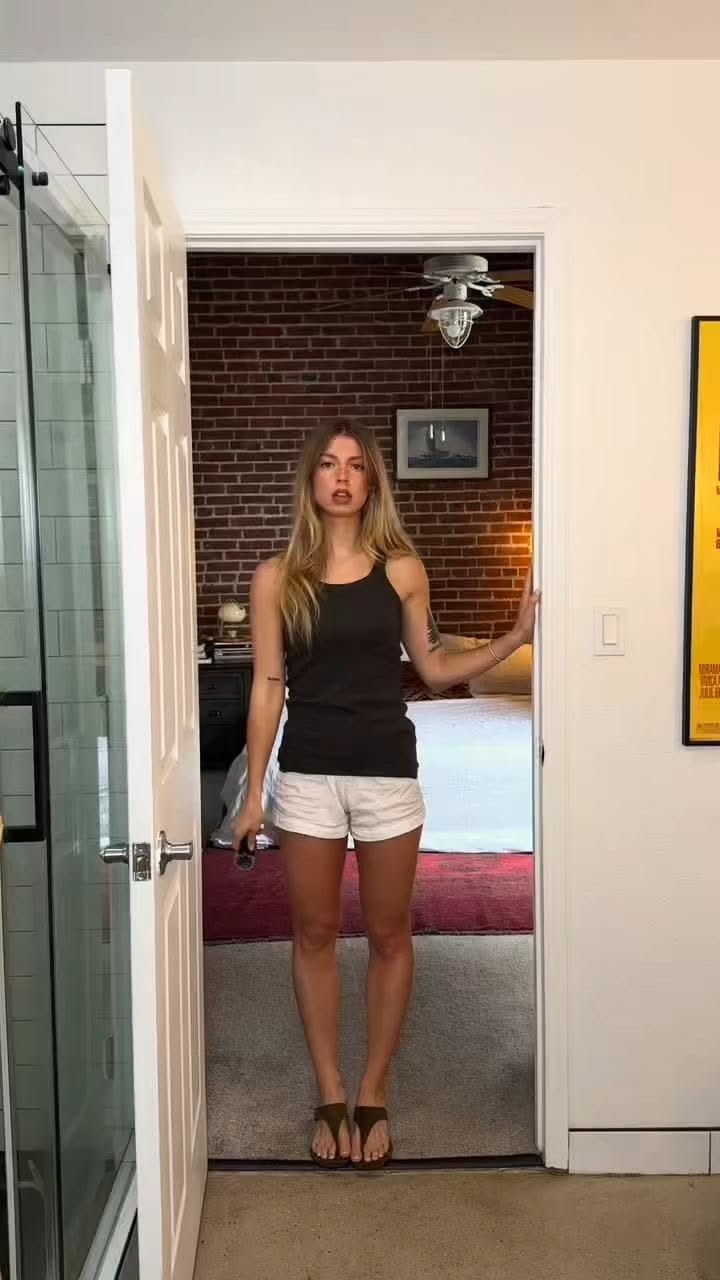 Woman in a tank top and shorts standing in a doorway