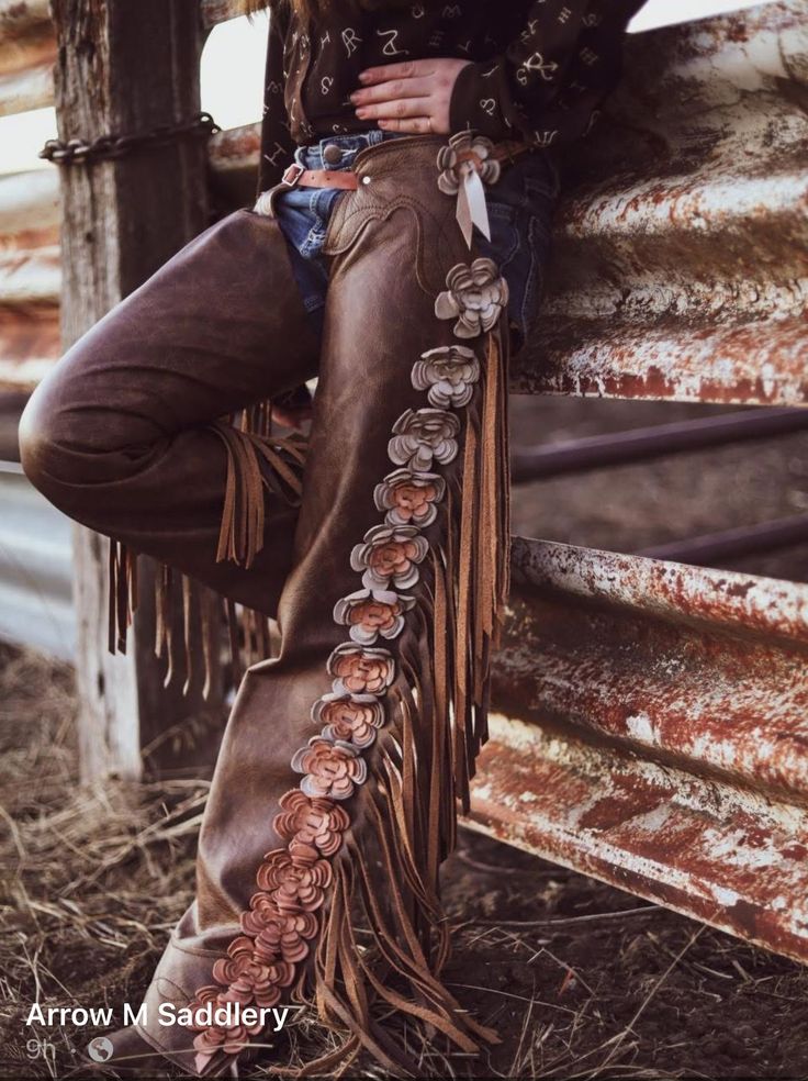 Person wearing leather chaps with floral embellishments and fringe