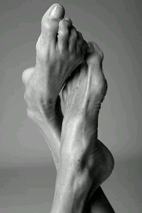 Black and white photograph of two bare feet crossed against a plain background