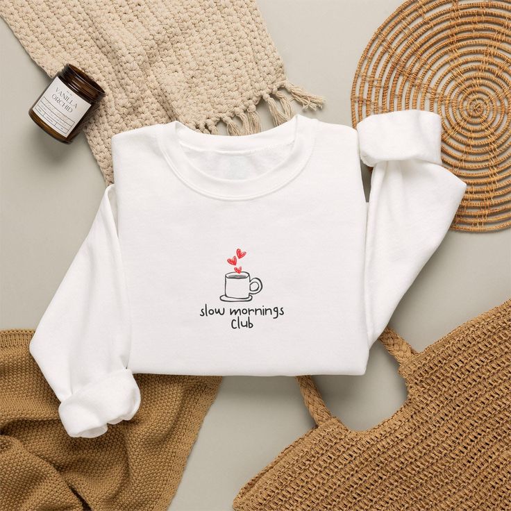 White sweatshirt with 'slow mornings club' graphic, surrounded by cozy items