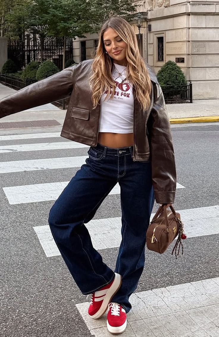 Woman in a brown leather jacket and wide leg jeans on a crosswalk