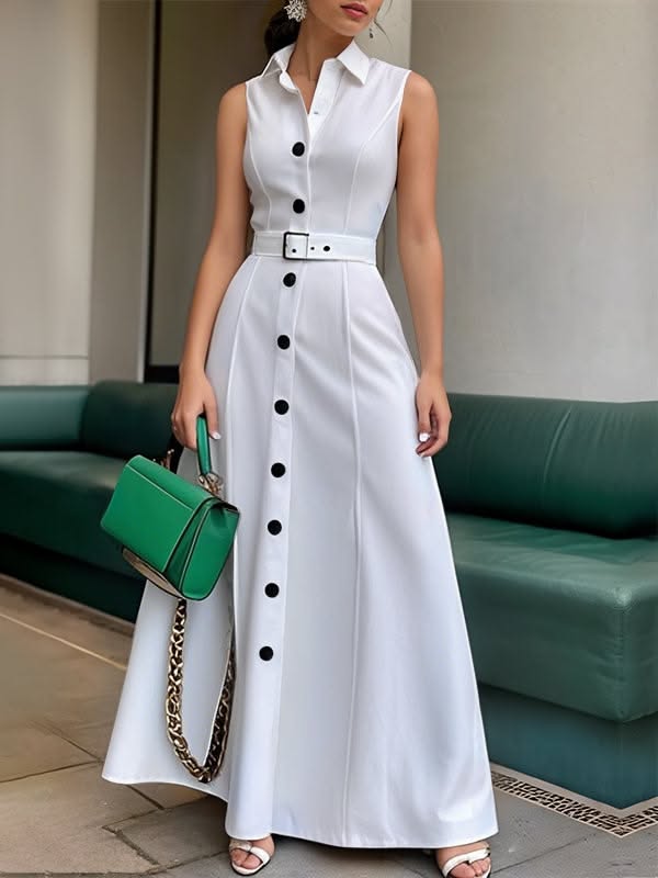 Woman in a white sleeveless dress with a green handbag standing outdoors