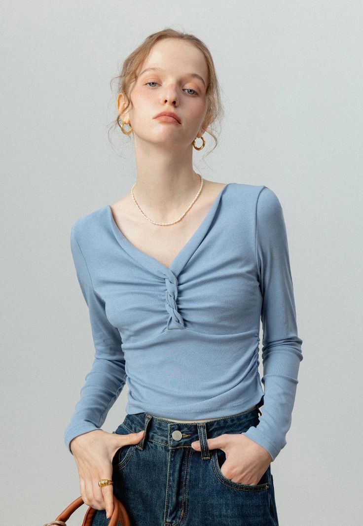 Woman in a blue long-sleeve top and denim jeans with a pearl necklace
