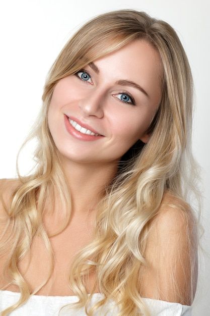 Blonde woman with blue eyes and wavy hair smiling at the camera