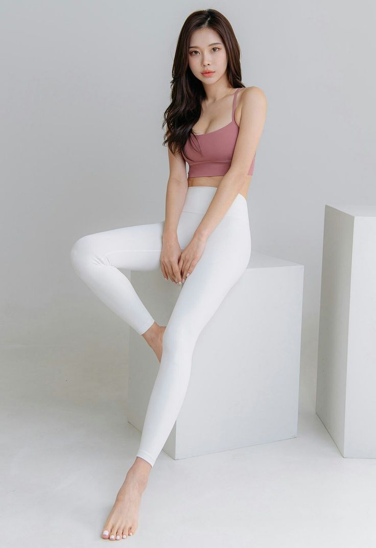 Woman in a pink sports bra and white leggings posing indoors