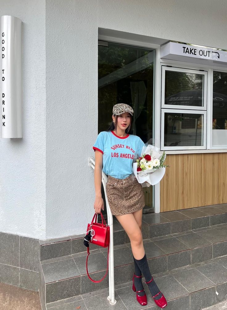 Woman in a blue t-shirt and leopard print skirt holding a bouquet outdoors