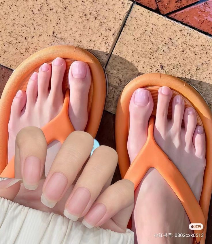 Close up of feet in orange flip flops with natural nails and pink toenails