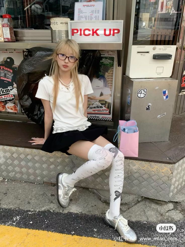 Blonde woman in glasses, mini skirt, and thigh-high socks sitting outdoors