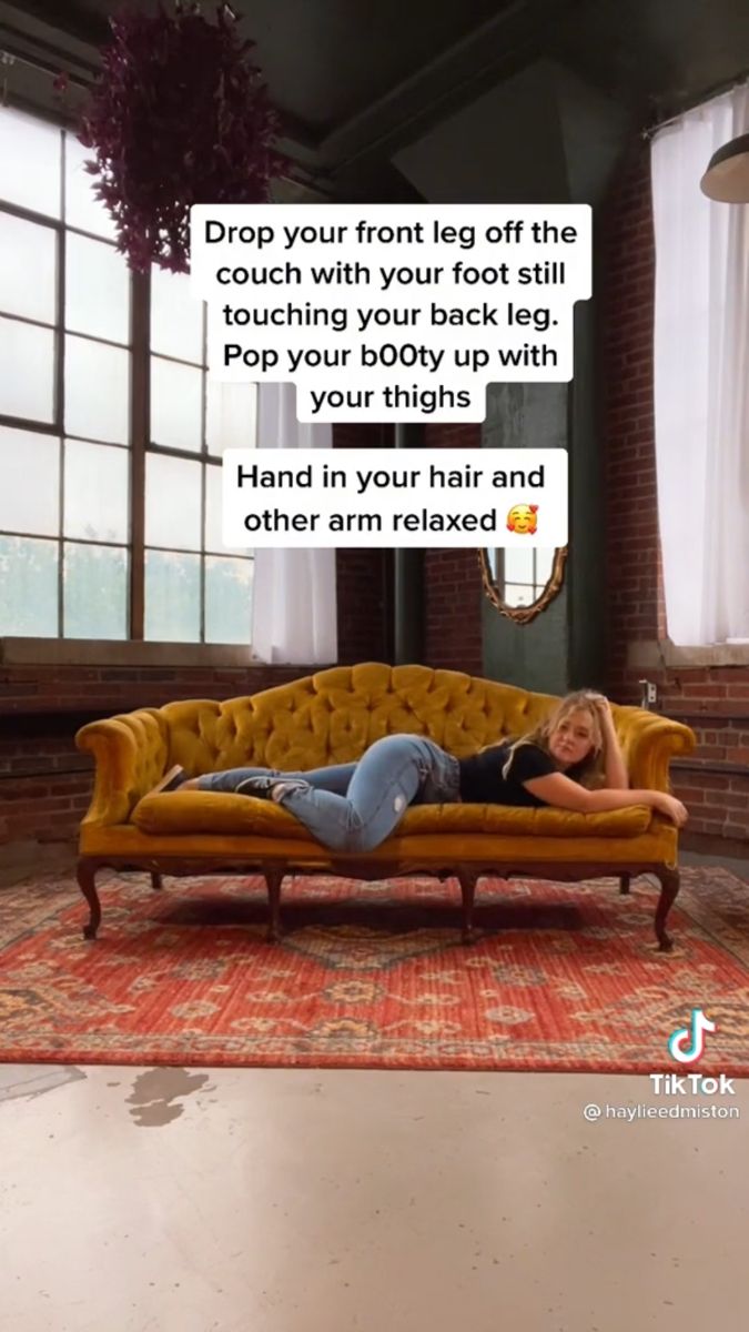 Woman in jeans and a black shirt posing on a yellow couch