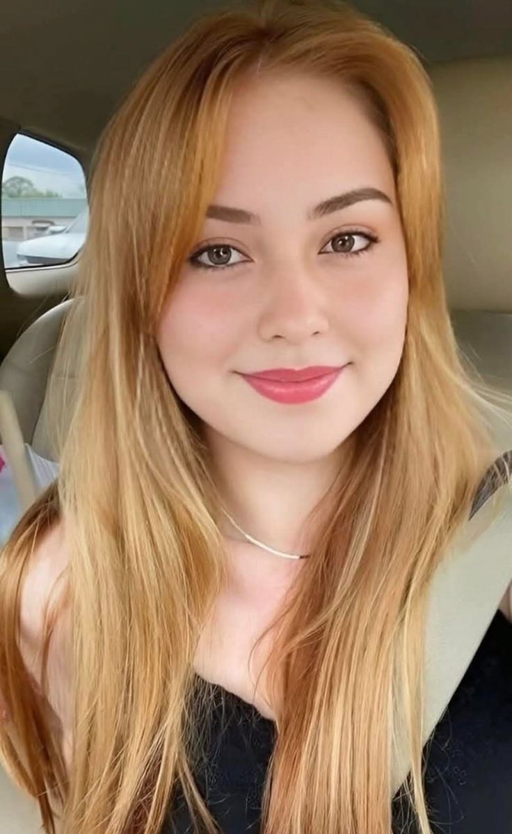 Woman with long blonde hair and red lipstick in a car