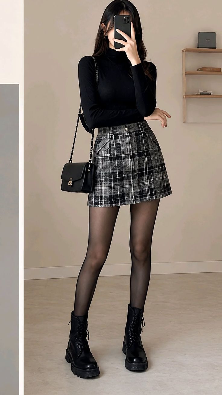 Woman in a black turtleneck and plaid skirt taking a mirror selfie