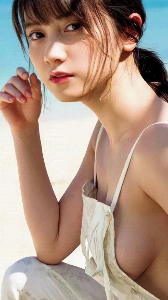 Woman with a ponytail on a beach, wearing a white top with sideboob visible