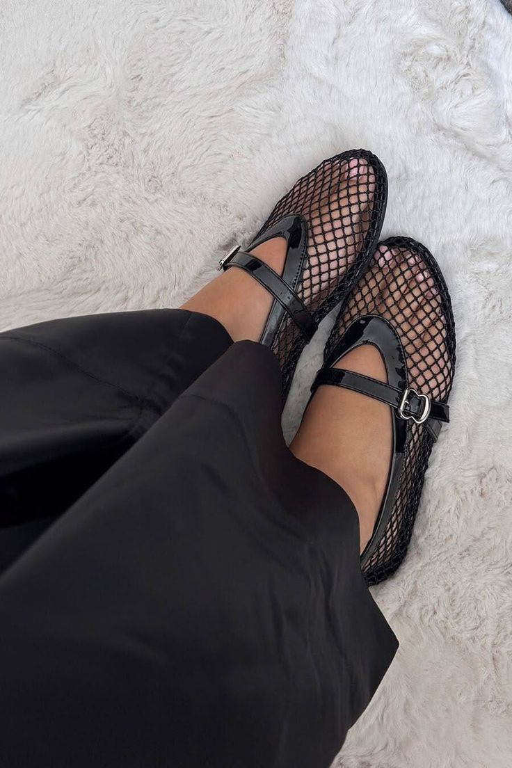 Person wearing black mesh Mary Jane shoes and black pants on a white furry rug