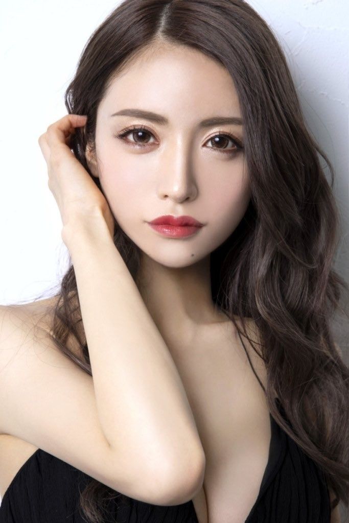 Woman with long brown hair and red lipstick, wearing a black top