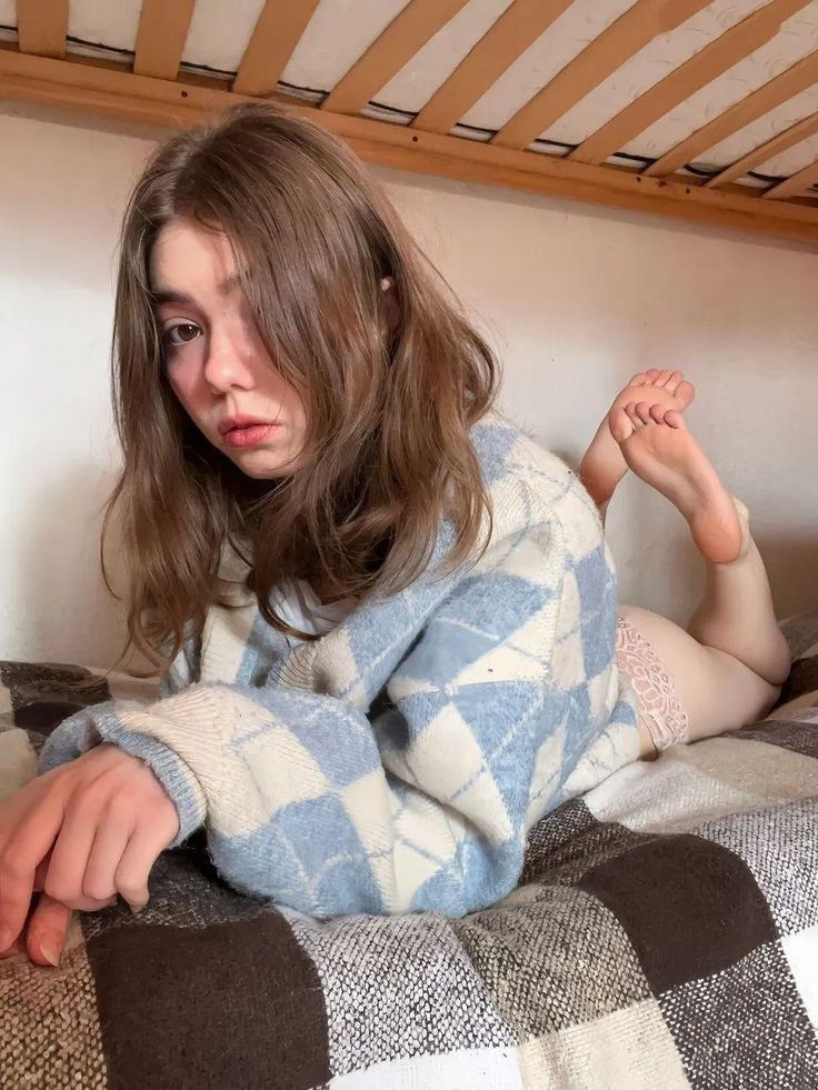 Woman in an argyle sweater and lace underwear lying on a bed