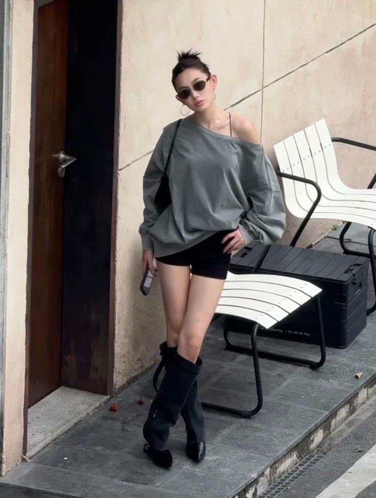Woman in an off-shoulder top, black shorts, and knee-high boots outdoors
