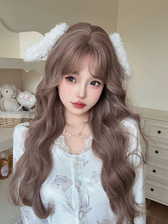 Woman with long wavy hair and a white ear headband wearing a cute top