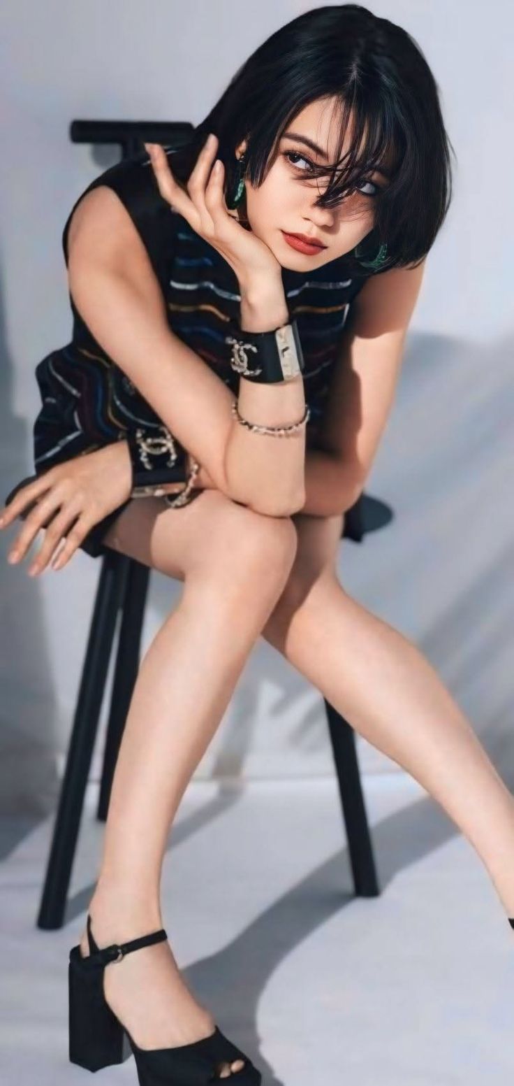 Woman with short black hair wearing a sleeveless top and high heels indoors