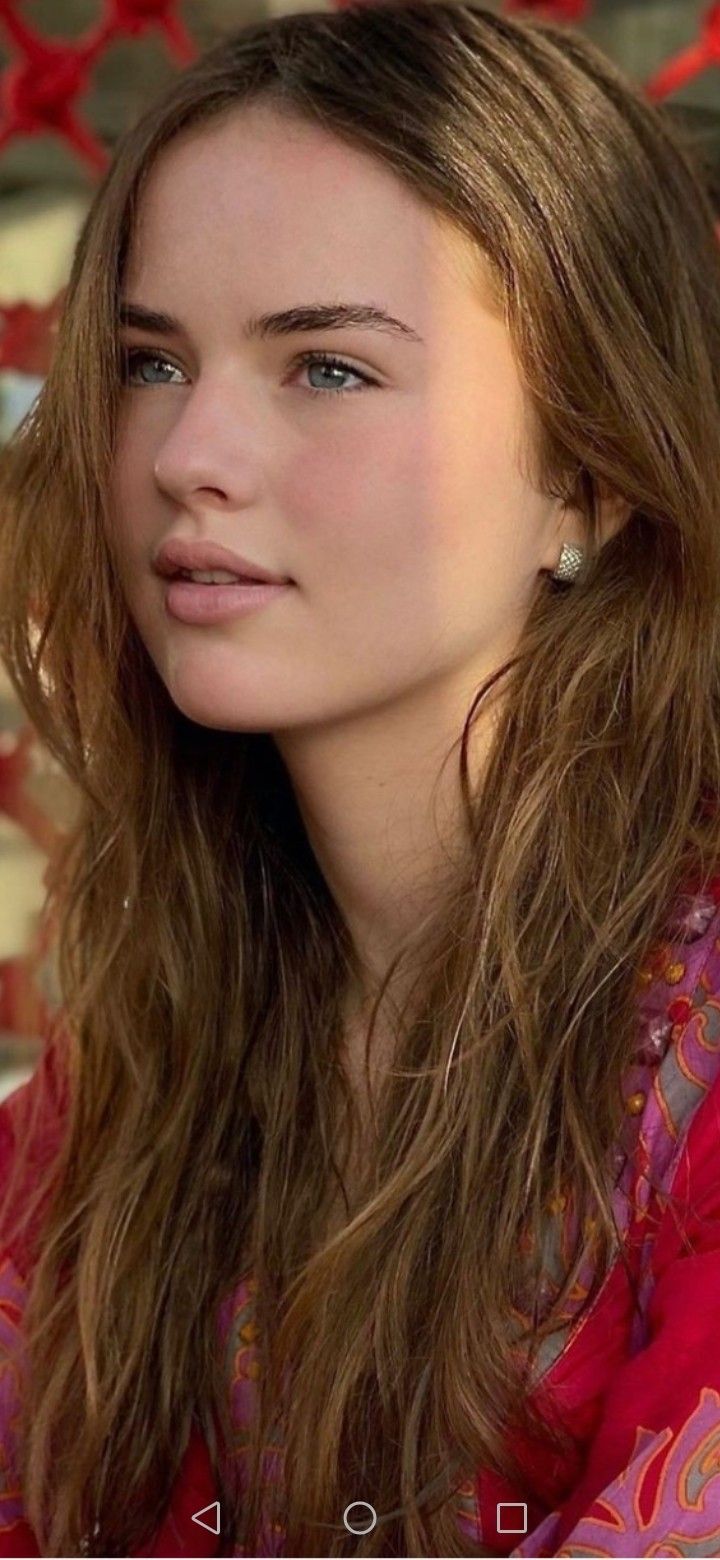 Woman with long brown hair and blue eyes wearing a red top