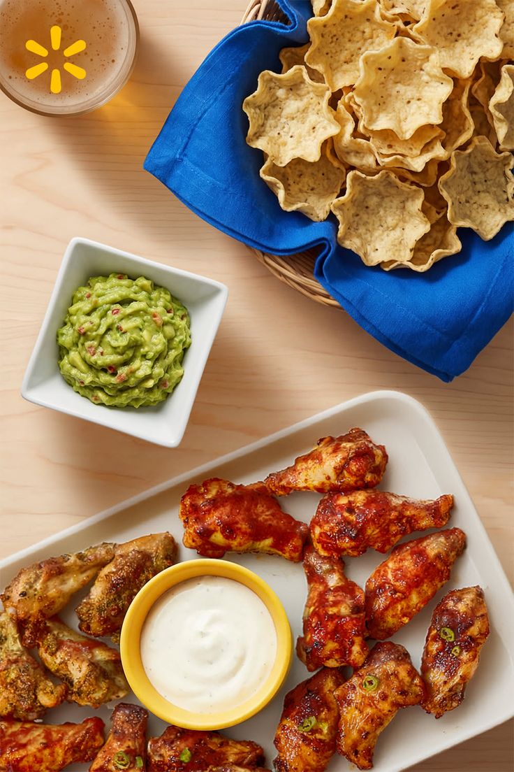 Chicken wings, guacamole, tortilla chips, and beer on a wooden table
